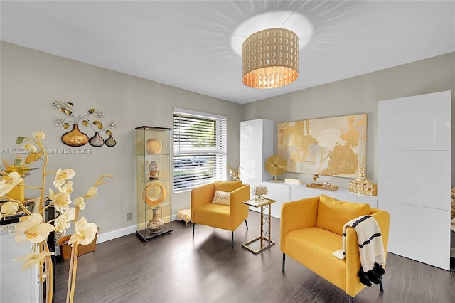 living area featuring dark wood-type flooring, a chandelier, and baseboards