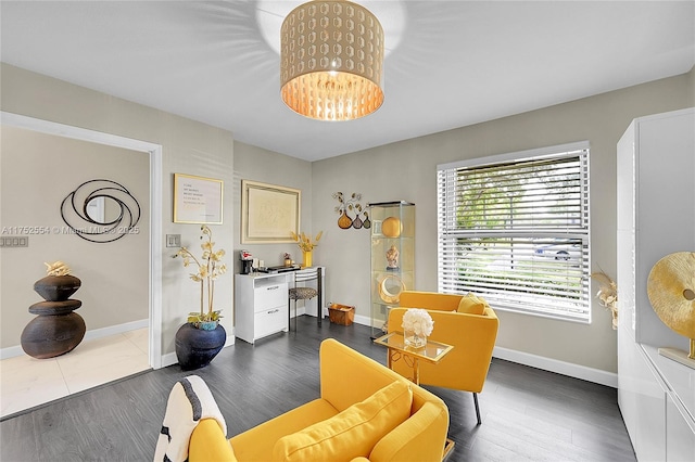 living area with baseboards, dark wood finished floors, and a notable chandelier