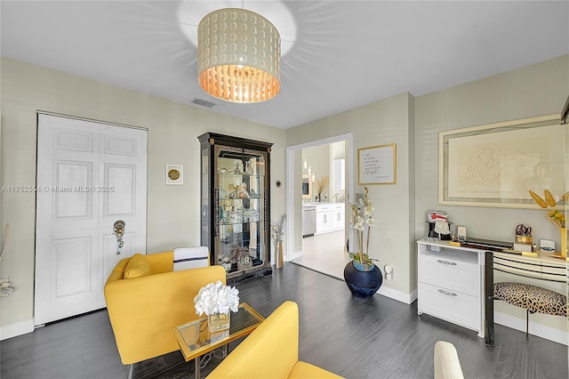 living area with a chandelier, dark wood-style flooring, visible vents, and baseboards