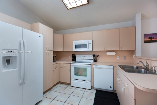 kitchen with light tile patterned floors, a peninsula, white appliances, a sink, and light countertops