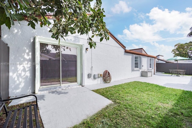 exterior space with a lawn, fence, a patio, and stucco siding