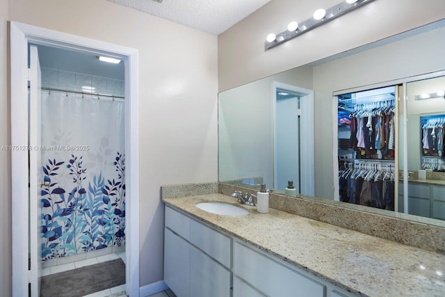 full bathroom featuring a shower with shower curtain, tile patterned floors, a spacious closet, a textured ceiling, and vanity