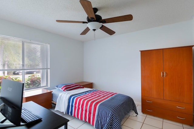 bedroom featuring light tile patterned floors, ceiling fan, and a textured ceiling