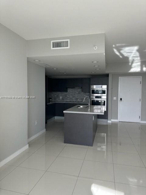 kitchen featuring light tile patterned floors, light countertops, stainless steel double oven, and visible vents