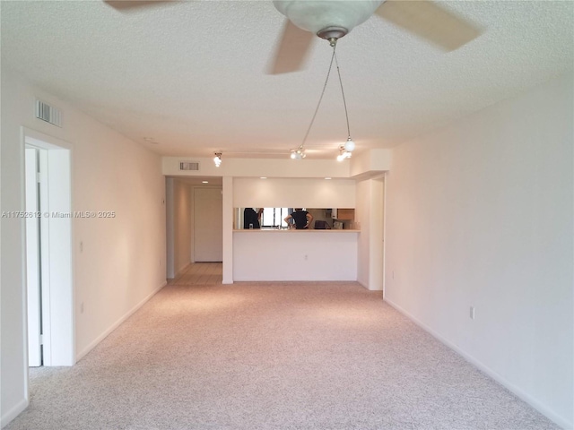 unfurnished living room featuring a textured ceiling, visible vents, and light colored carpet