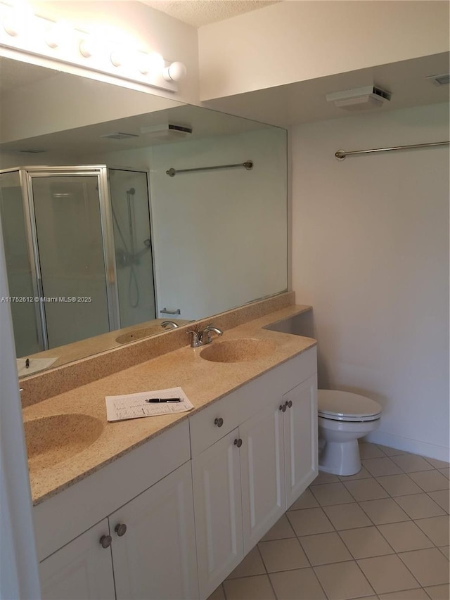 full bath featuring double vanity, a stall shower, tile patterned flooring, and a sink