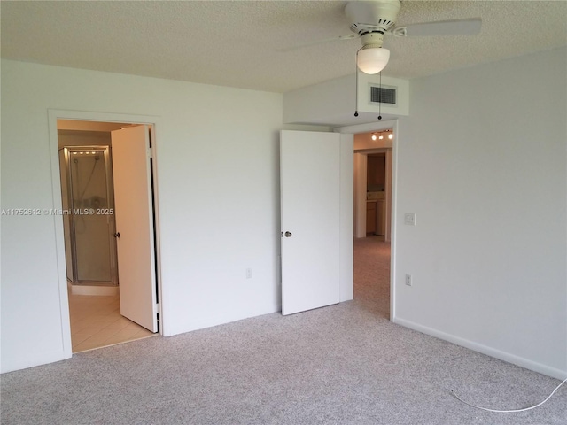 unfurnished bedroom featuring ensuite bath, visible vents, a textured ceiling, and light colored carpet