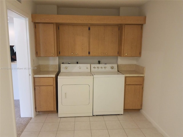 washroom featuring cabinet space, washer and clothes dryer, baseboards, and light tile patterned floors