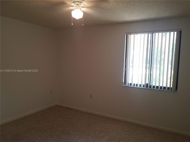 carpeted spare room with a textured ceiling, ceiling fan, and baseboards