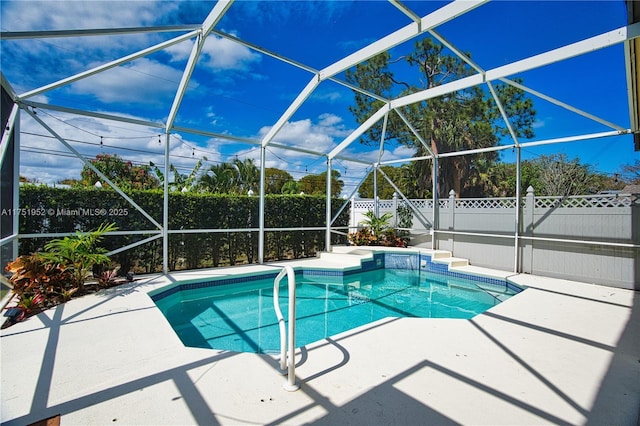 view of pool featuring glass enclosure, a patio area, a fenced backyard, and a fenced in pool