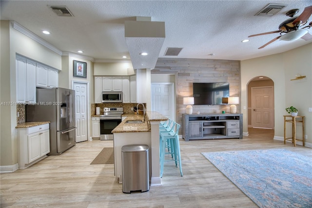 kitchen featuring stainless steel appliances, a breakfast bar, a peninsula, and white cabinetry