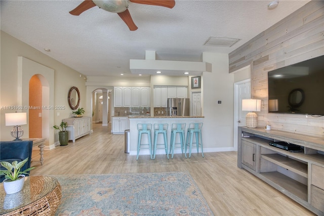 kitchen featuring white cabinetry, light wood-style floors, high end fridge, light countertops, and backsplash