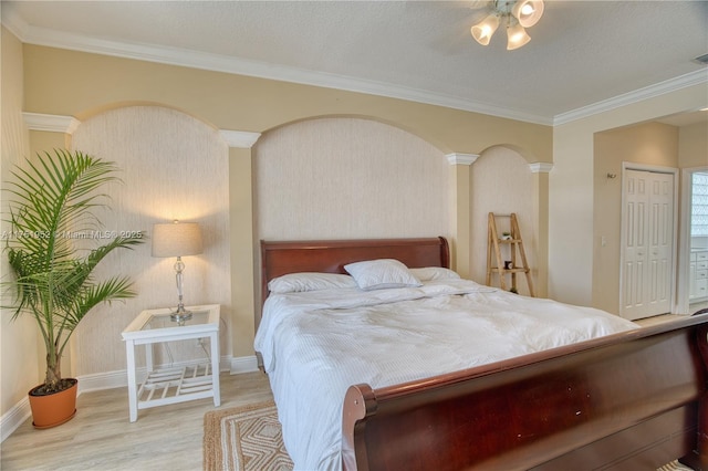 bedroom with crown molding, decorative columns, light wood-style flooring, and baseboards