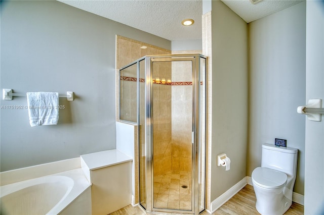 bathroom featuring toilet, wood finished floors, a garden tub, a textured ceiling, and a shower stall