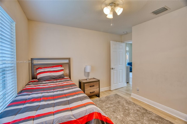 bedroom featuring light wood-style floors, visible vents, baseboards, and a ceiling fan