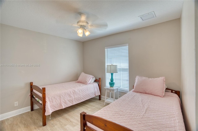 bedroom with baseboards, ceiling fan, a textured ceiling, and light wood-style floors