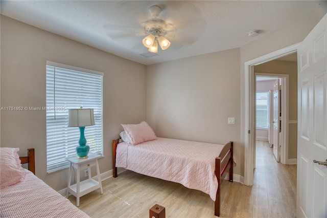 bedroom featuring visible vents, light wood-type flooring, a ceiling fan, and baseboards