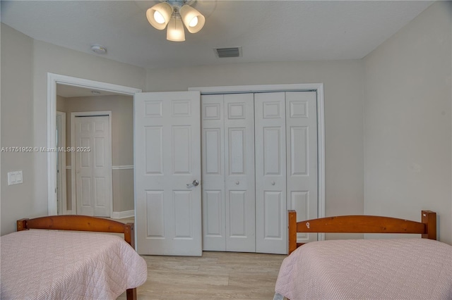 bedroom featuring light wood-type flooring, visible vents, and a closet