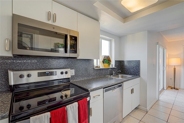 kitchen featuring stainless steel appliances, dark countertops, a sink, and white cabinets