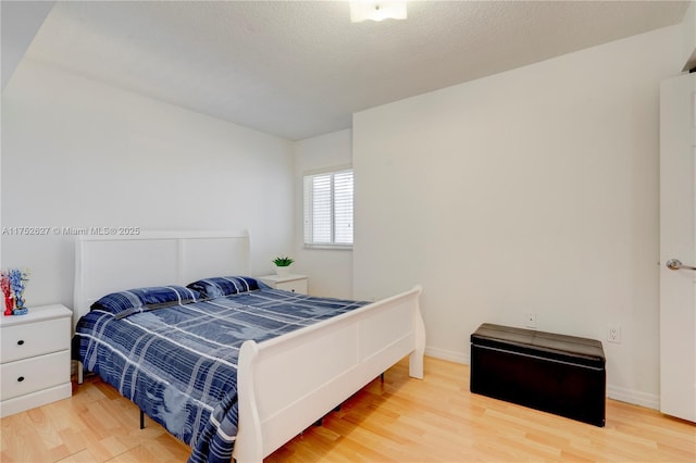 bedroom featuring a textured ceiling, wood finished floors, and baseboards