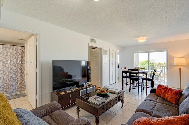 living area featuring light tile patterned floors, visible vents, and a textured ceiling