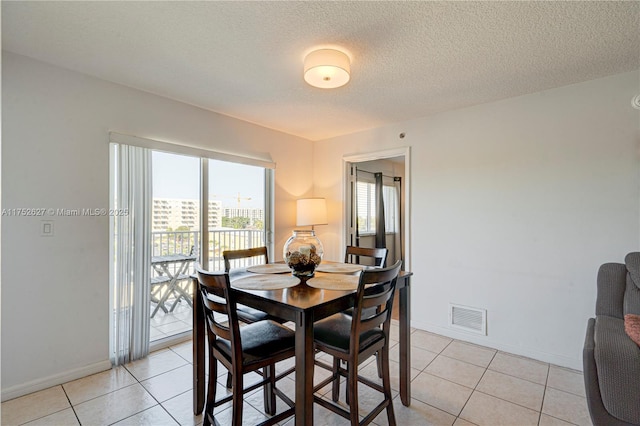 dining room with light tile patterned floors, a textured ceiling, visible vents, and baseboards