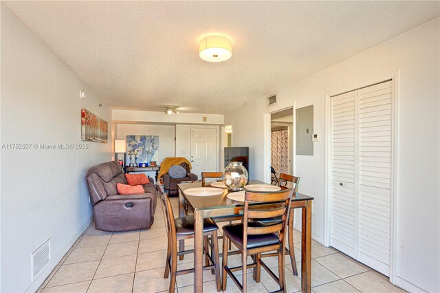 dining room featuring electric panel, visible vents, a textured ceiling, and light tile patterned flooring