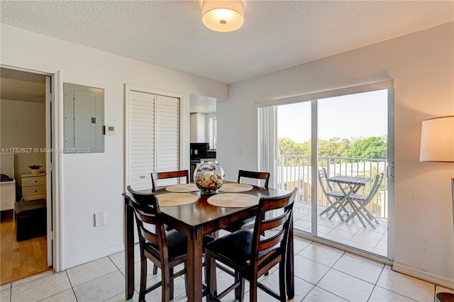 dining space featuring electric panel, a textured ceiling, baseboards, and light tile patterned flooring