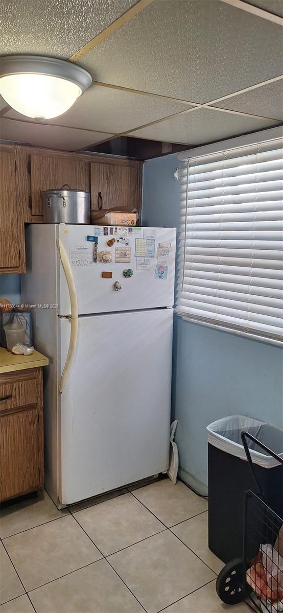 kitchen featuring brown cabinets, freestanding refrigerator, light countertops, and light tile patterned floors