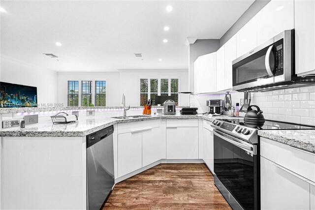 4704 SW 160th Ave Unit 224, Miramar, FL 33027 - kitchen with appliances with stainless steel finishes, white cabinetry, wood finished floors, tasteful backsplash, and light stone countertops