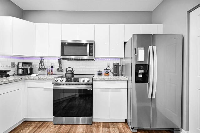 4704 SW 160th Ave Unit 224, Miramar, FL 33027 - kitchen featuring stainless steel appliances, white cabinetry, wood finished floors, backsplash, and light stone countertops