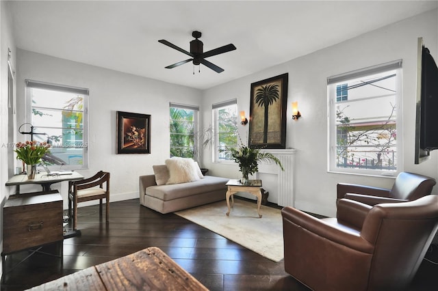 living area with dark wood finished floors, baseboards, and ceiling fan