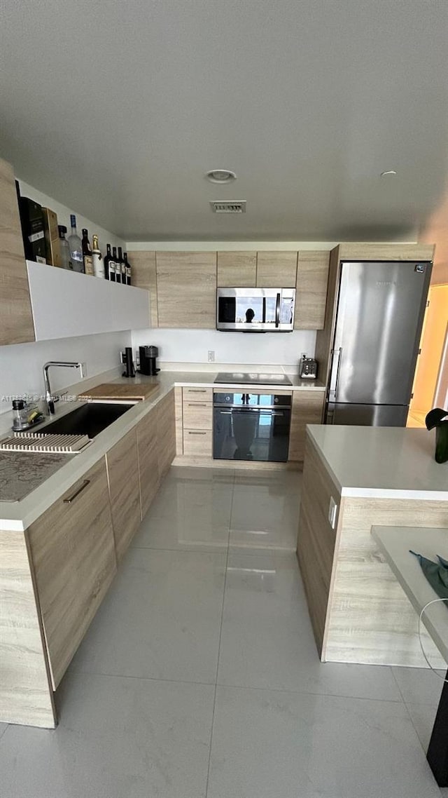 kitchen with visible vents, modern cabinets, light countertops, black appliances, and a sink