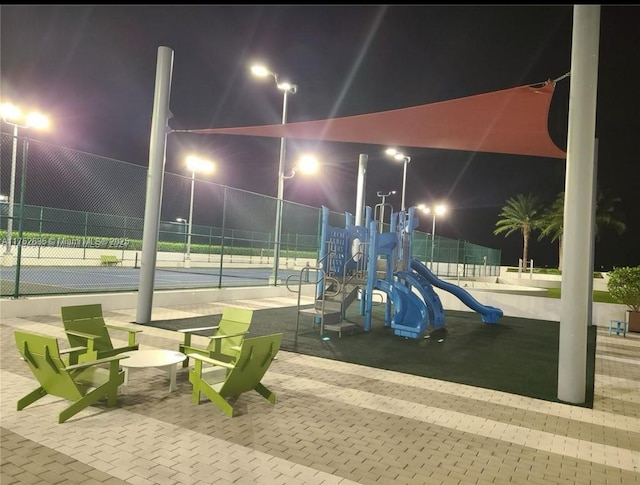 playground at night with a tennis court, playground community, and fence