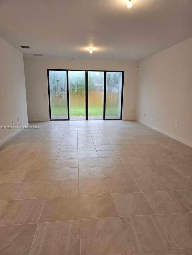 spare room featuring baseboards and light tile patterned flooring