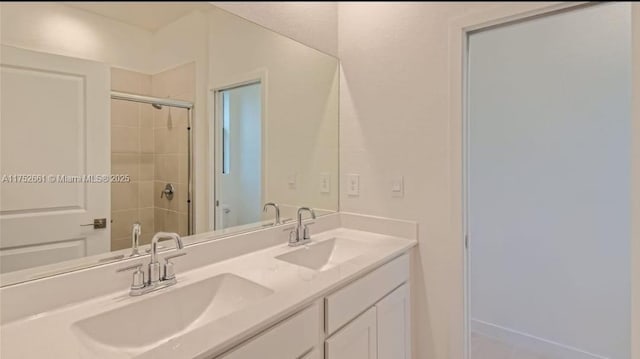 bathroom featuring tiled shower, a sink, and double vanity