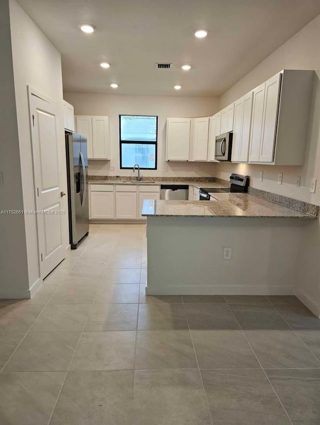 kitchen featuring stainless steel appliances, a peninsula, a sink, visible vents, and white cabinets