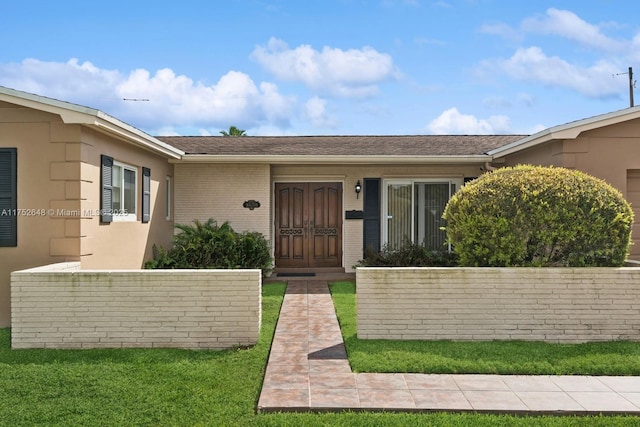 property entrance with a yard and brick siding