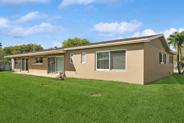 back of property with a patio, a lawn, and stucco siding