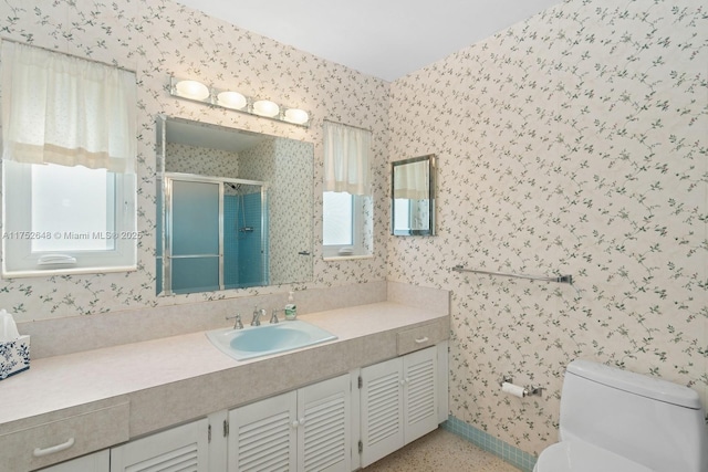 full bath with toilet, vanity, a shower stall, baseboards, and wallpapered walls