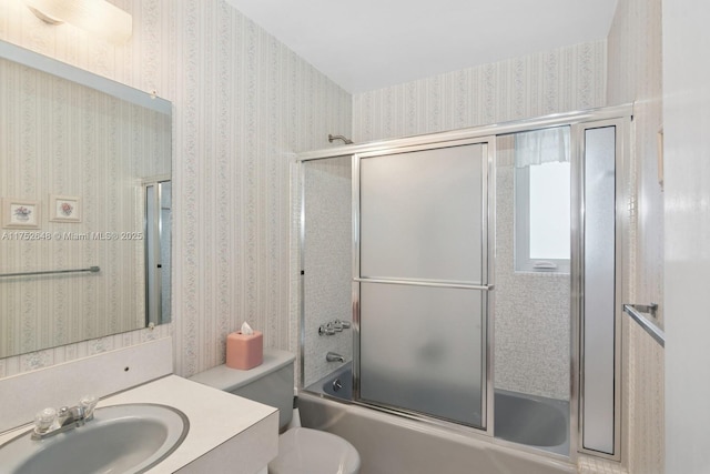 full bathroom featuring shower / bath combination with glass door, vanity, toilet, and wallpapered walls