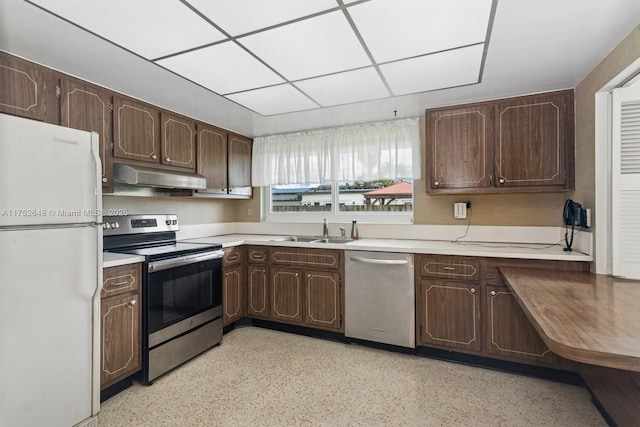 kitchen with stainless steel appliances, dark brown cabinets, light countertops, under cabinet range hood, and a sink