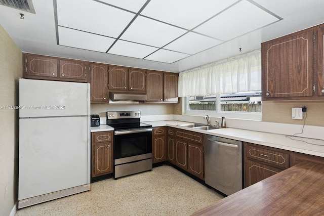 kitchen featuring stainless steel appliances, light countertops, a sink, dark brown cabinetry, and extractor fan