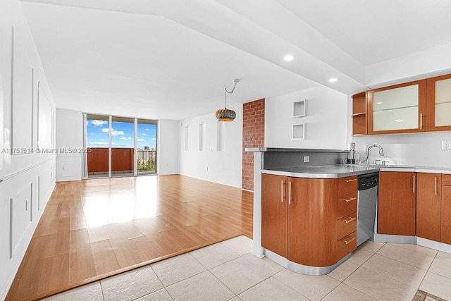 kitchen featuring light countertops, brown cabinets, dishwasher, glass insert cabinets, and pendant lighting