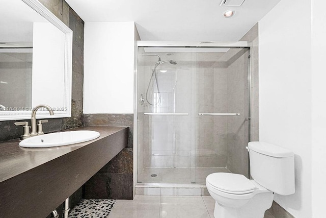 bathroom with visible vents, toilet, a stall shower, a sink, and tile patterned flooring