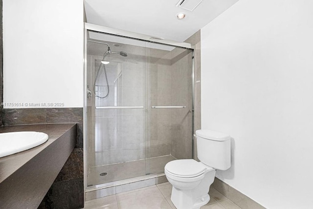 full bath with a stall shower, visible vents, toilet, tile patterned flooring, and tile walls