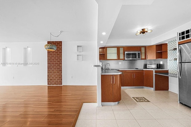 kitchen with brown cabinets, decorative light fixtures, open shelves, appliances with stainless steel finishes, and glass insert cabinets