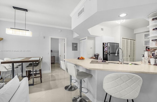 kitchen featuring light tile patterned floors, visible vents, a breakfast bar, freestanding refrigerator, and a sink