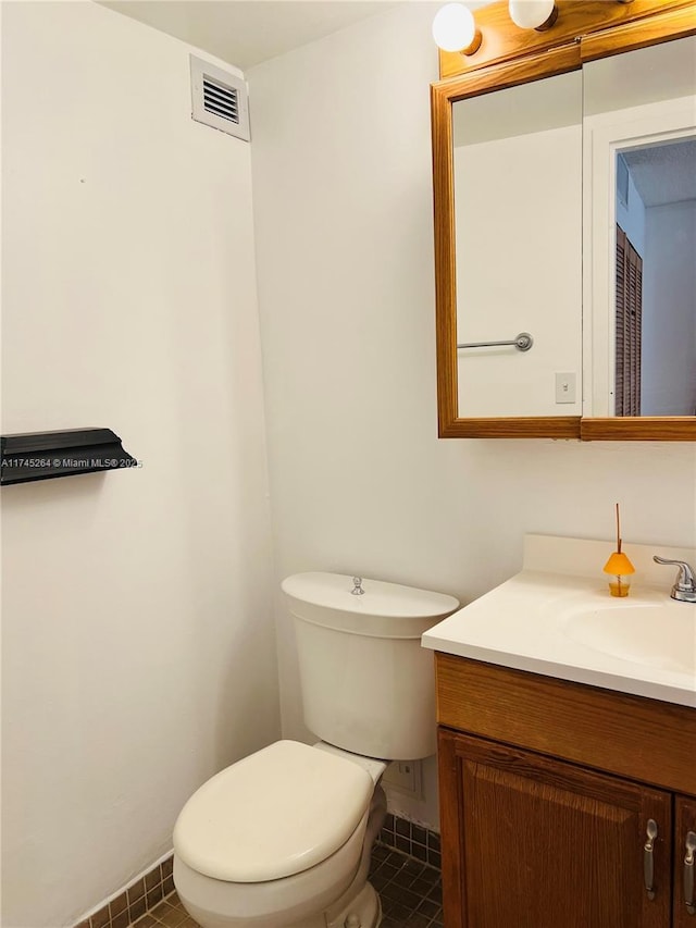 half bath with toilet, tile patterned flooring, and vanity