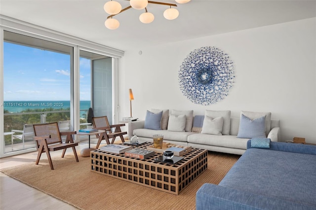 living room featuring a wall of windows, a water view, wood finished floors, and a notable chandelier